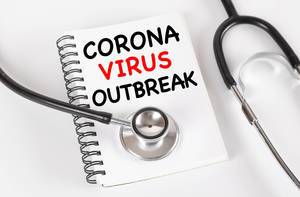 Stethoskop liegt auf einem Notizbuch mit den Worten Corona Virus Outbreak auf weißem Hintergrund
