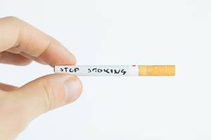 Stop smoking written on a cigarette and held by a man