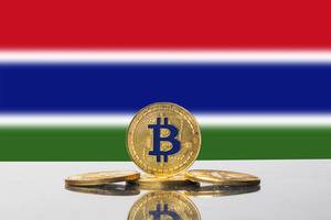 Strahlende goldene Bitcoins vor der Nationalflagge des afrikanischen Landes Gambia