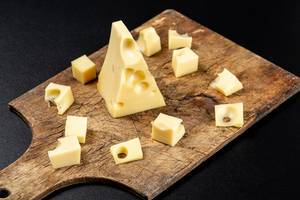 Stückchen von Maasdamer Käse auf einem rustikalen Holzbrett