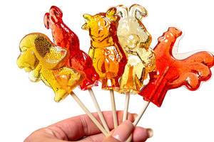 Sugar candies in the form of animals and cartoon characters on sticks in the hand