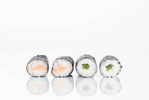 Sushi Rollen gefüllt mit grünem Paprika und Lachs im weißen HIntergrund