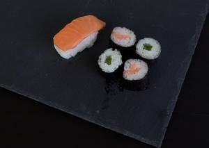 Sushis gefüllt mit Lachs und grünem Paprika auf schwarzem Tisch