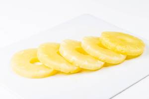 Süße Ananas Scheiben aus der Dose auf einem weißen Küchenbrett