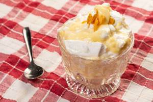 Süße Nachspeise aus Creme in dekorativer Dessertschale aus Glas neben Löffel