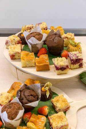 Süße Nachspeisen angerichtet auf runden Holzbrettchen mit Kuchen, Früchten und Muffins, beim Mittagessen im AXA-Gebäude während des Barcamps OMWest19 in Köln