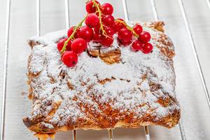 Sweet strudel with powdered sugar and a sprig of fresh red currant