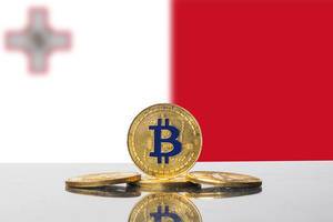 Symmetrisch angeordnete Bitcoins vor der Flagge von Malta