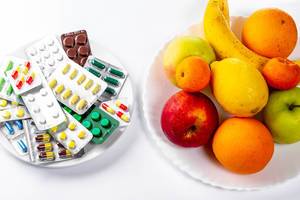 Tablets and fresh fruit on white background. The concept of choosing between a healthy diet and treatment