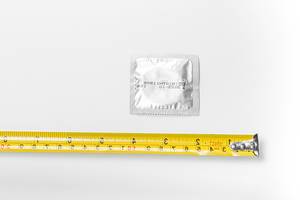 Tape measure and condom on a white background. Sizing concept (Flip 2019)