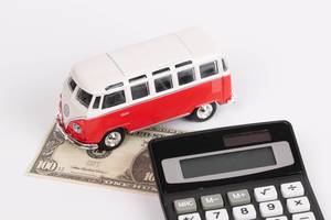 Taschenrechner, Einhundert-US-Dollar-Banknote und VW Spielzeug-Bus