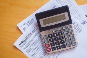 Tax form 1040 and a calculator. US tax form law document on a wooden desk. Business concept