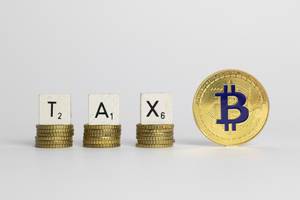 TAX - Schriftzug - Steuern - auf Münzen mit einem Bitcoin auf weißem Hintergrund