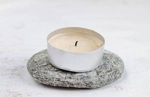 Tea light on a stone and a wooden surface