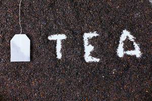 Teebeutel und das Wort "Tea" in getrockneten Teeblüten