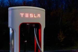 Tesla Supercharter-Ladesäule mit beleuchtetem LED-Schriftzug bei Nacht