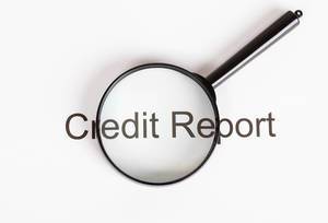 Text Credit Report unter einer Lupe mit weißem Hintergrund