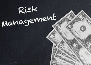 Text RISK MANAGEMENT (Risikomanagement) auf schwarzer Tafel neben Dollarnoten