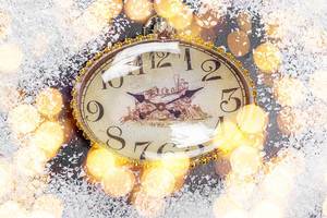 The concept of approaching the New Year. The clock on the snow and bokeh