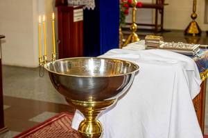 The concept of child baptism in the Christian Church. A bowl of water for the baptism of the child and burning candles