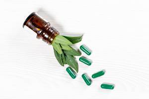 The concept of herbal medicines. Green capsules and leaves, top view (Flip 2019)
