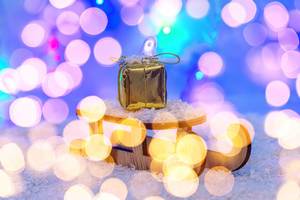 The concept of preparation for winter holidays. Sleigh with gift on snow with bokeh (Flip 2019)