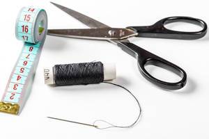 The concept of sewing - thread with needle and scissors