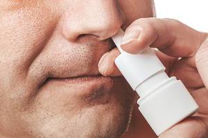 The concept of the treatment of the common cold at home. Male nose and nasal spray close up (Flip 2019)