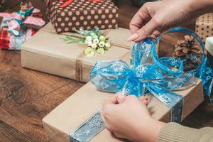 The girl ties a bow on the gift box. The concept of preparing for Christmas (Flip 2019)