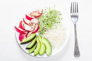 The view from the top rice with slices of radish, avocado and micro-greens onions