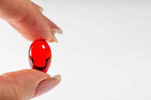 The woman is holding a red capsule painkiller