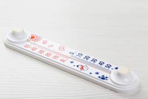 Thermometer showing temperature in degrees Celsius on white wooden background