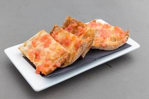 Thin bread and tomato topping on a white plate at the Restaurant of Hotel 1898 in Barcelona, Spain