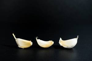Three garlic cloves on a black surface