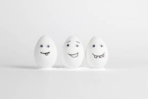 Three happy eggs with eyes and cheeky faces