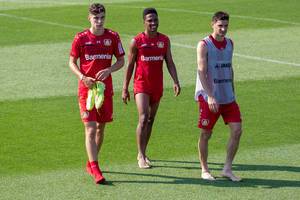 Three soccer players Lucas Alario, Wendell and Kai Havertz leaving the pitch happy and barefoot after their training in Germany
