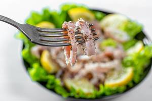 Tintenfischringe auf einer Gabel, mit einem gesunden Salat im Hintergrund