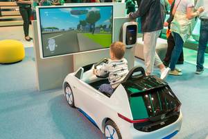 Tiny driving school: Child in a VW toy car, playing a driving simulation game at car exhibition IAA