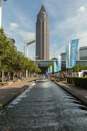Tiny river with small bridges & IAA flags at the exhibition site, with view of the MesseTurm / exhibition tower in Frankfurt, Germany