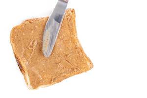 Toastbrot mit Erdnussbutter und einem Messer, vor weißem Hintergrund