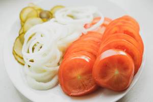 Tomaten, Zwiebeln und Gurkenscheiben auf einem weißen Teller
