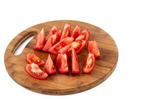 Tomatenscheiben als gesunde Salatbeigabe, liegen auf einem runden Küchenbrettchen