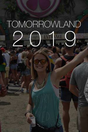 Tomorrowland 2019 Bild zeigt Festivalbesucherin mit Sonnenbrille und Drink vor der Bühne