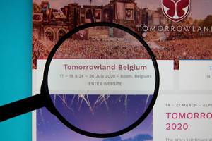 Tomorrowland Belgium 2020 dates on a computer screen with a magnifying glass