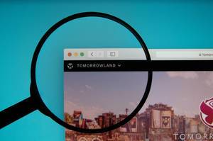 Tomorrowland website on a computer screen with a magnifying glass