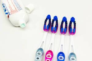 Toothbrushes and toothpaste on a white surface