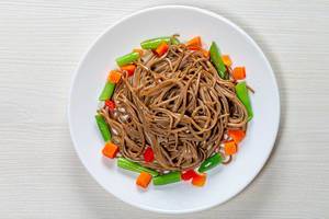 Top view buckwheat noodles with asparagus, carrots and sweet peppers on a white wooden background (Flip 2019)