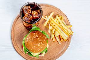 Top view Burger, fries and iced drink on round kitchen Board