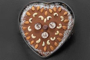 Top view chocolate heart cake with nuts and coconut on black background (Flip 2019)