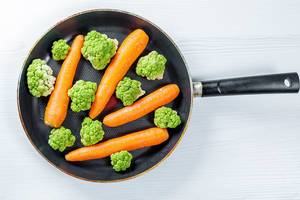 Top view cooking carrots and broccoli in a frying pan